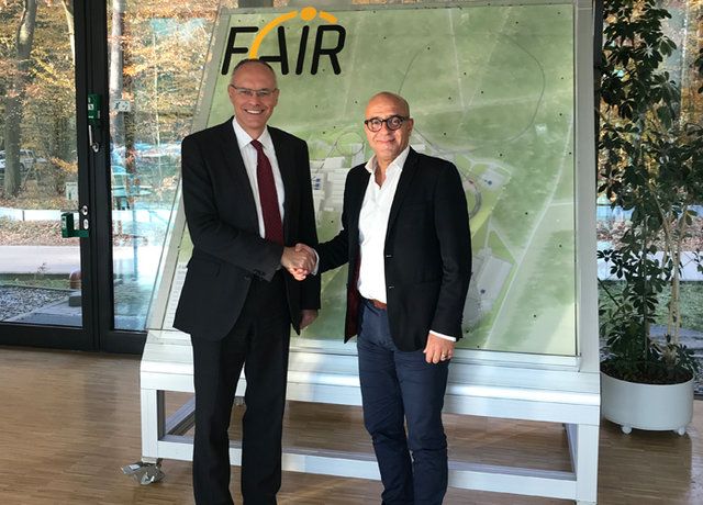 Faiҫal Azaiez and Paolo Giubellino shaking hands in front of a model of the FAIR facility