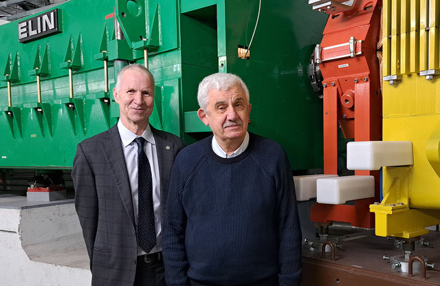 Zwei Männer stehen vor einem grünen und einem gelben Magneten des GSI-Fragmentseparators. Zwei Männer stehen vor einem grünen und einem gelben Magneten des GSI-Fragmentseparators.